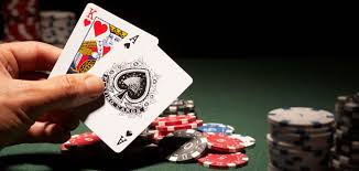 hand holding playing cards with poker table and chips on the background